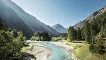 Eine gebirgige Landschaft mit klarem Fluss, dichten Wäldern und felsigem Gelände.