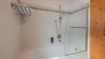 Une salle de bain avec une douche à parois de verre, une baignoire blanche et un porte-serviettes.