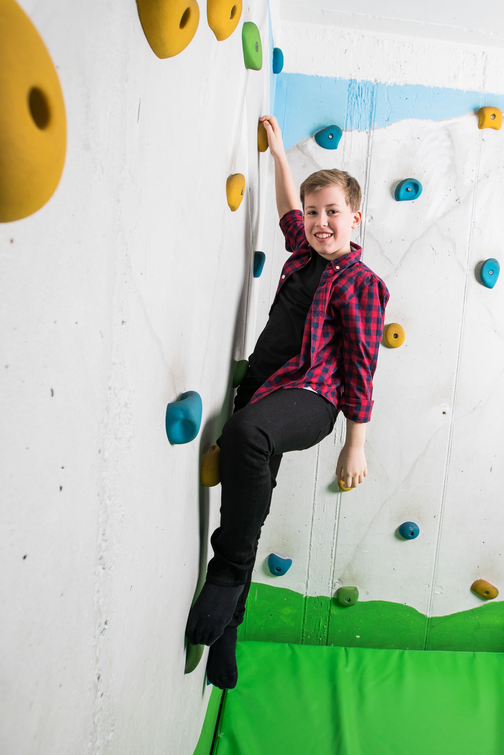 Eine Person klettert eine Wand mit bunten Tritten.