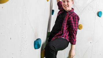 Eine Person klettert eine Wand mit bunten Tritten.