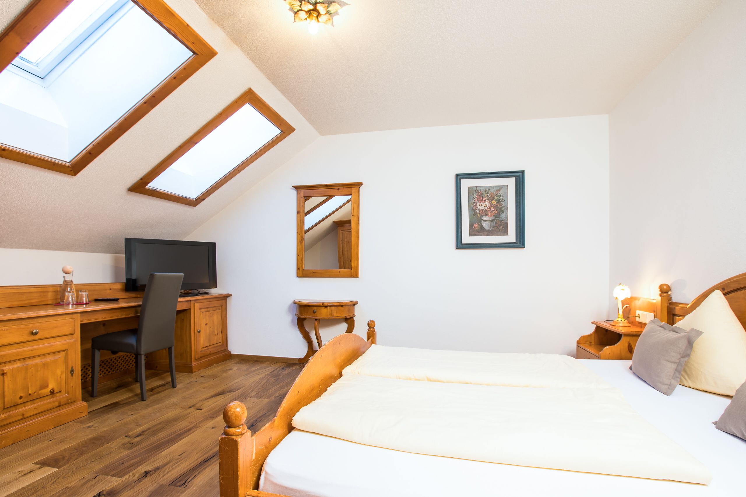 Une chambre à coucher avec un lit en bois, un bureau, une chaise, un téléviseur et une lucarne.