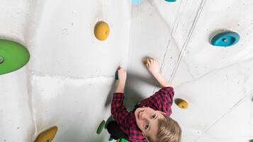 Un enfant qui grimpe sur un mur d’escalade équipé de prises de différentes couleurs.