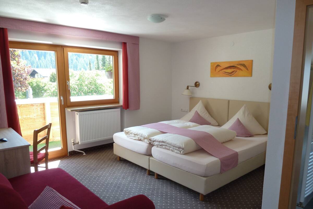 A bedroom with a bed, a chair, a radiator, a window, and a painting on the wall.