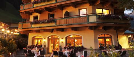 A hotel with multiple balconies, outdoor dining area, and a sign reading "Sport HOTEL Kirchle."
