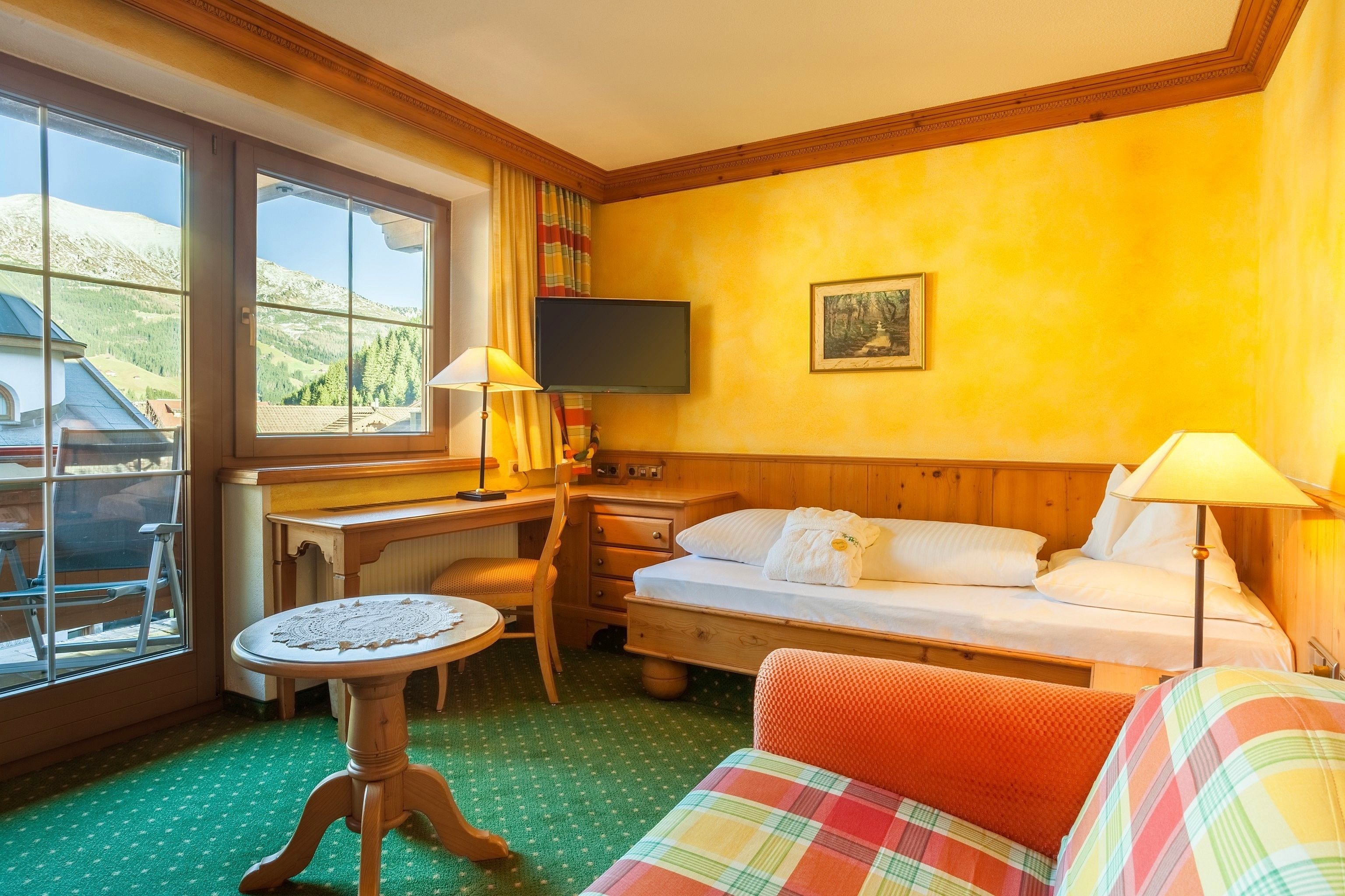 Een hotelkamer met een bed, bureau, stoel, klein tafeltje en een televisie.