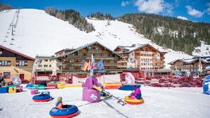 A ski resort with snow tubing facilities, wooden buildings, and a snowy mountain backdrop. - Hotel Salzburger Hof (Altenmarkt im Pongau)