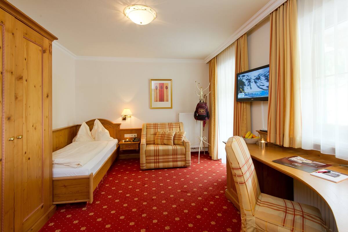 A hotel room with a bed, a sofa, a desk, and a television.