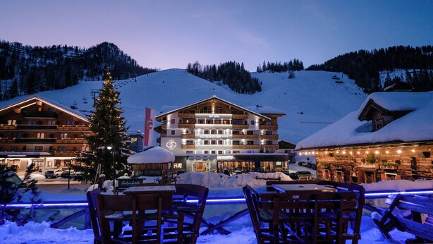 A hotel with multiple floors, outdoor seating, and a snow-covered mountain backdrop. - Hotel Salzburger Hof (Altenmarkt im Pongau)