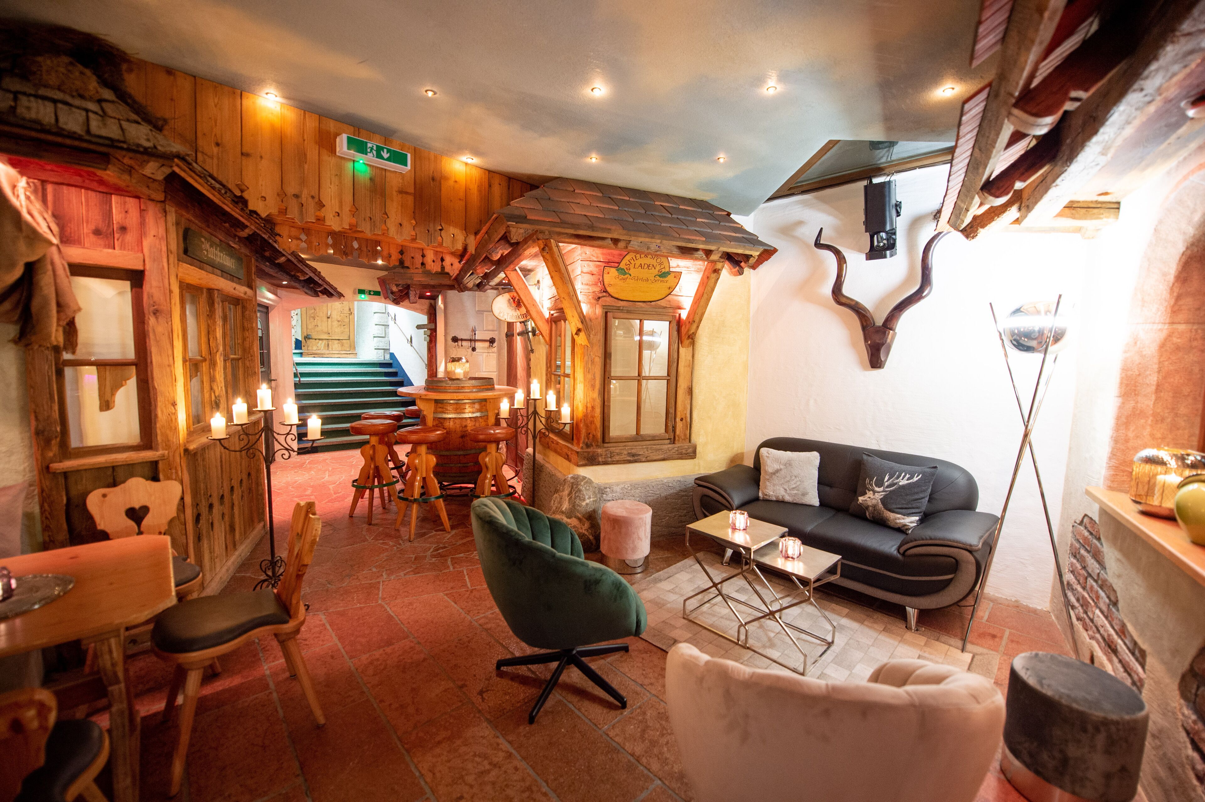 A cozy interior with wooden walls, a sofa, chairs, a table, and a fireplace.