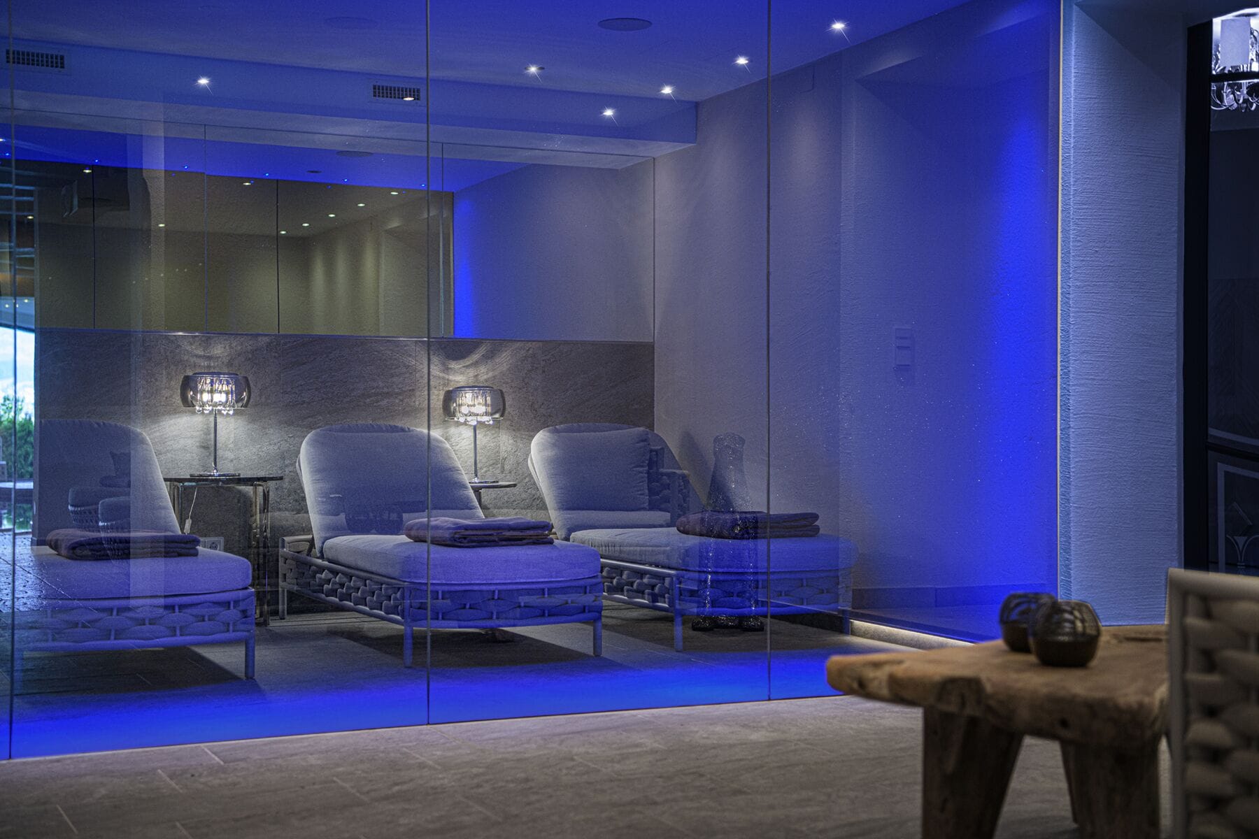 Un espace détente moderne comprenant trois fauteuils confortables, une petite table et une cloison en verre.