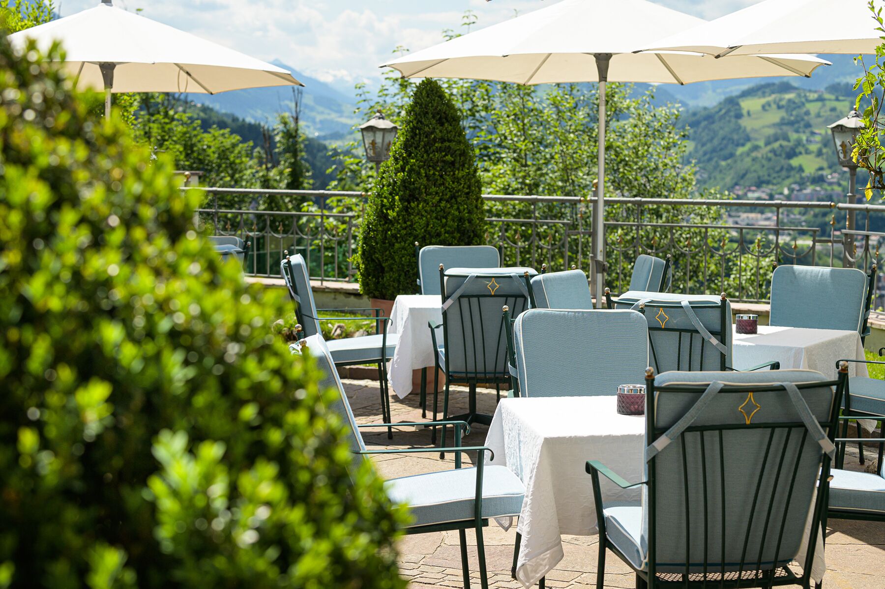 Outdoor seating with tables and chairs, umbrellas, and a view of the mountains.
