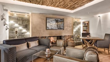 Cozy seating area with a sectional sofa and armchairs, fireplace, and large painting.