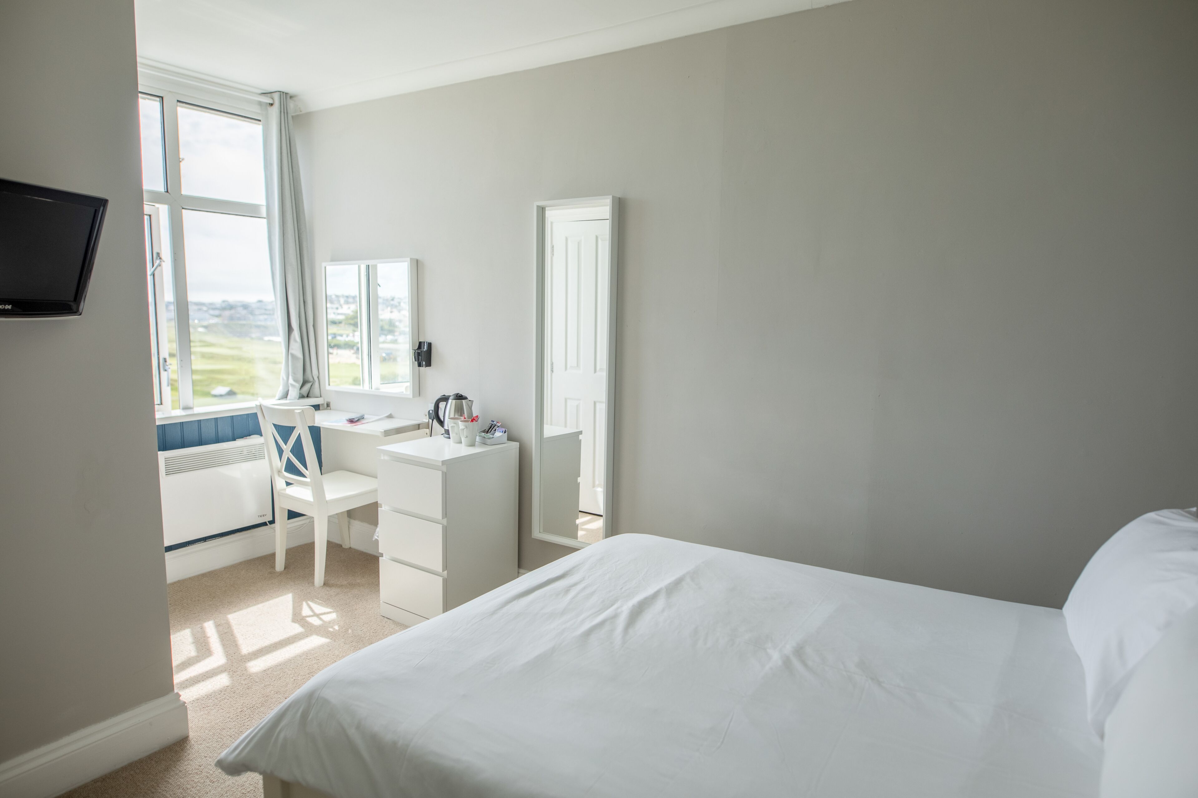 A bedroom with a bed, a desk, and a chair.