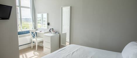 A bedroom with a bed, a desk, and a chair.