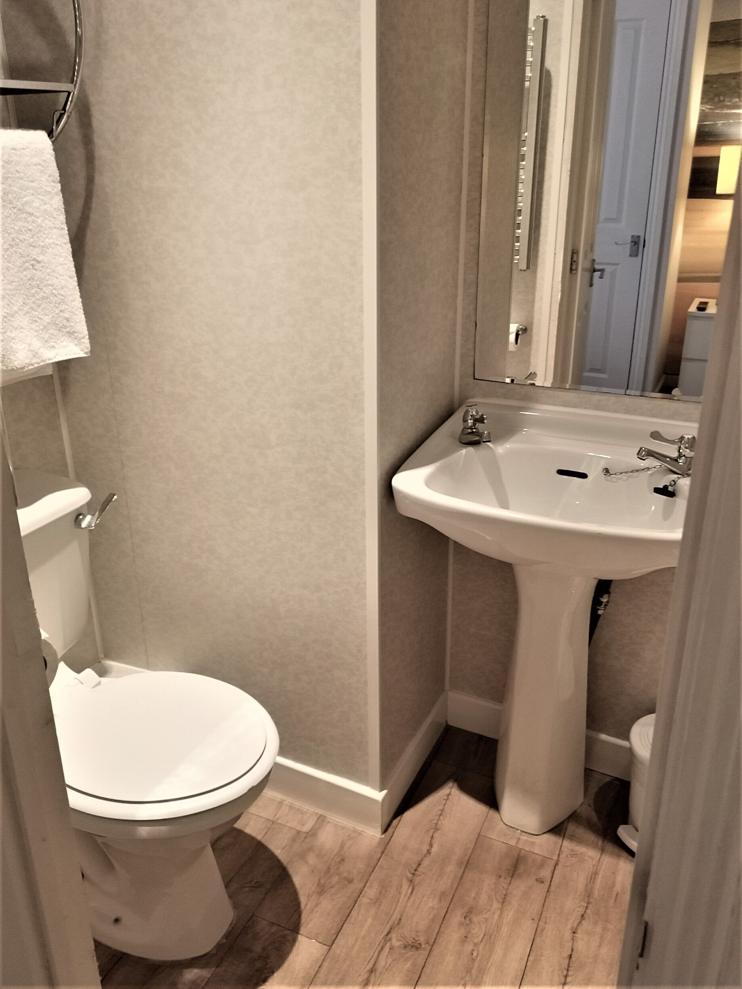 Een badkamer met toilet, wastafel en spiegel.