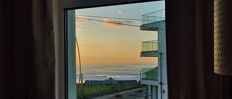 Vista a través de una ventana que muestra un edificio moderno y un cuerpo de agua.