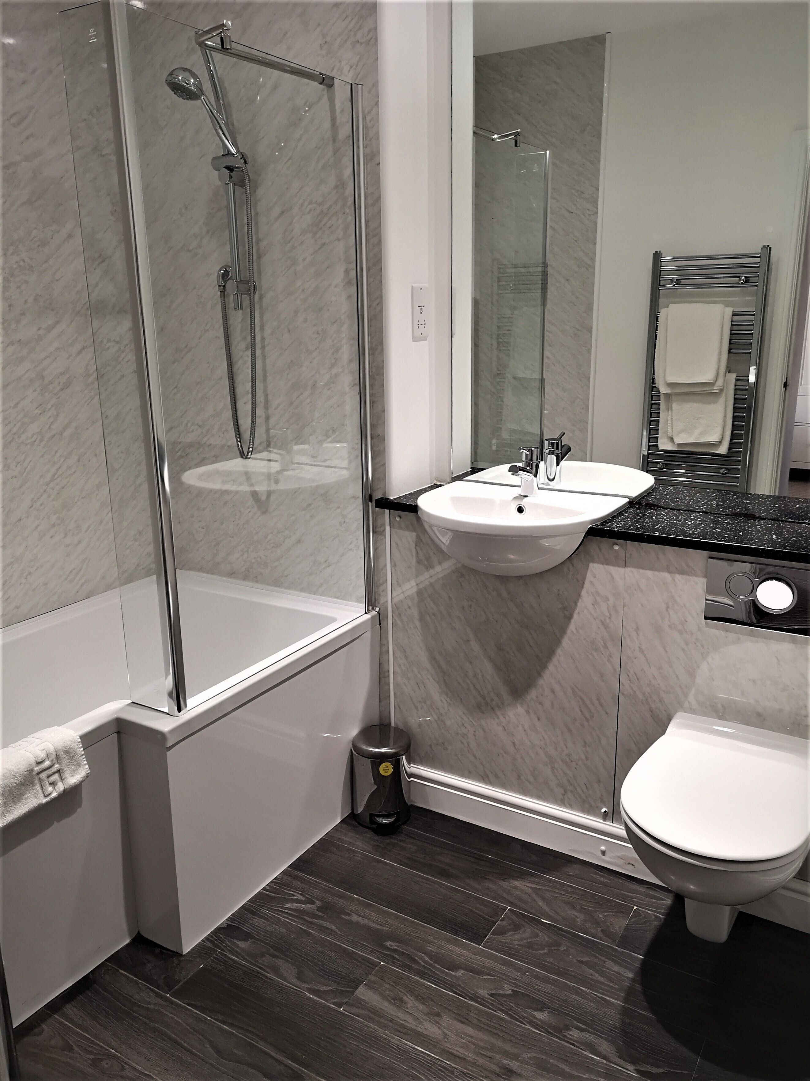 Uma casa de banho moderna com chuveiro envidraçado, lavatório branco e sanita.