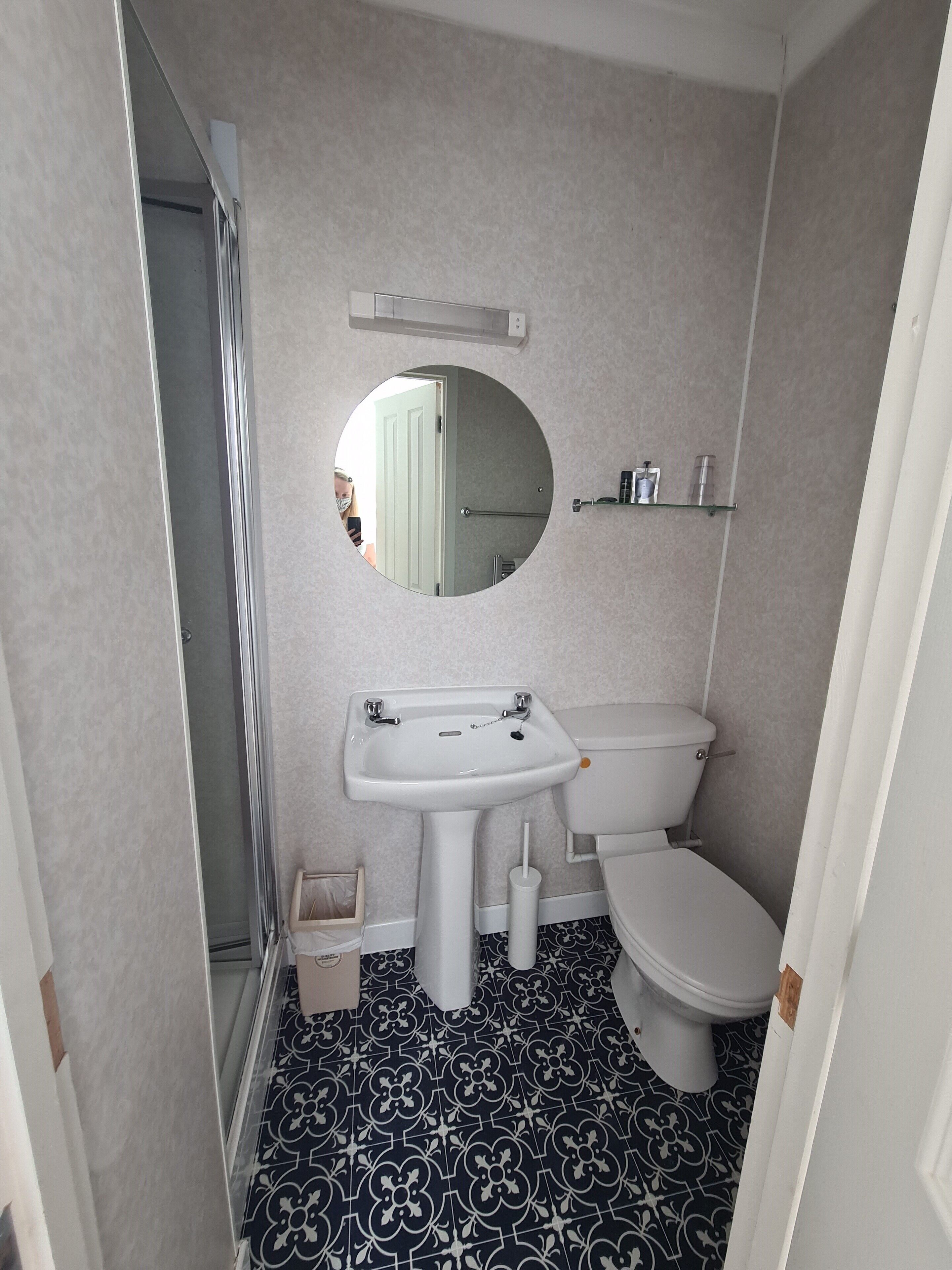 Et lille badeværelse med toilet, håndvask og rundt spejl.