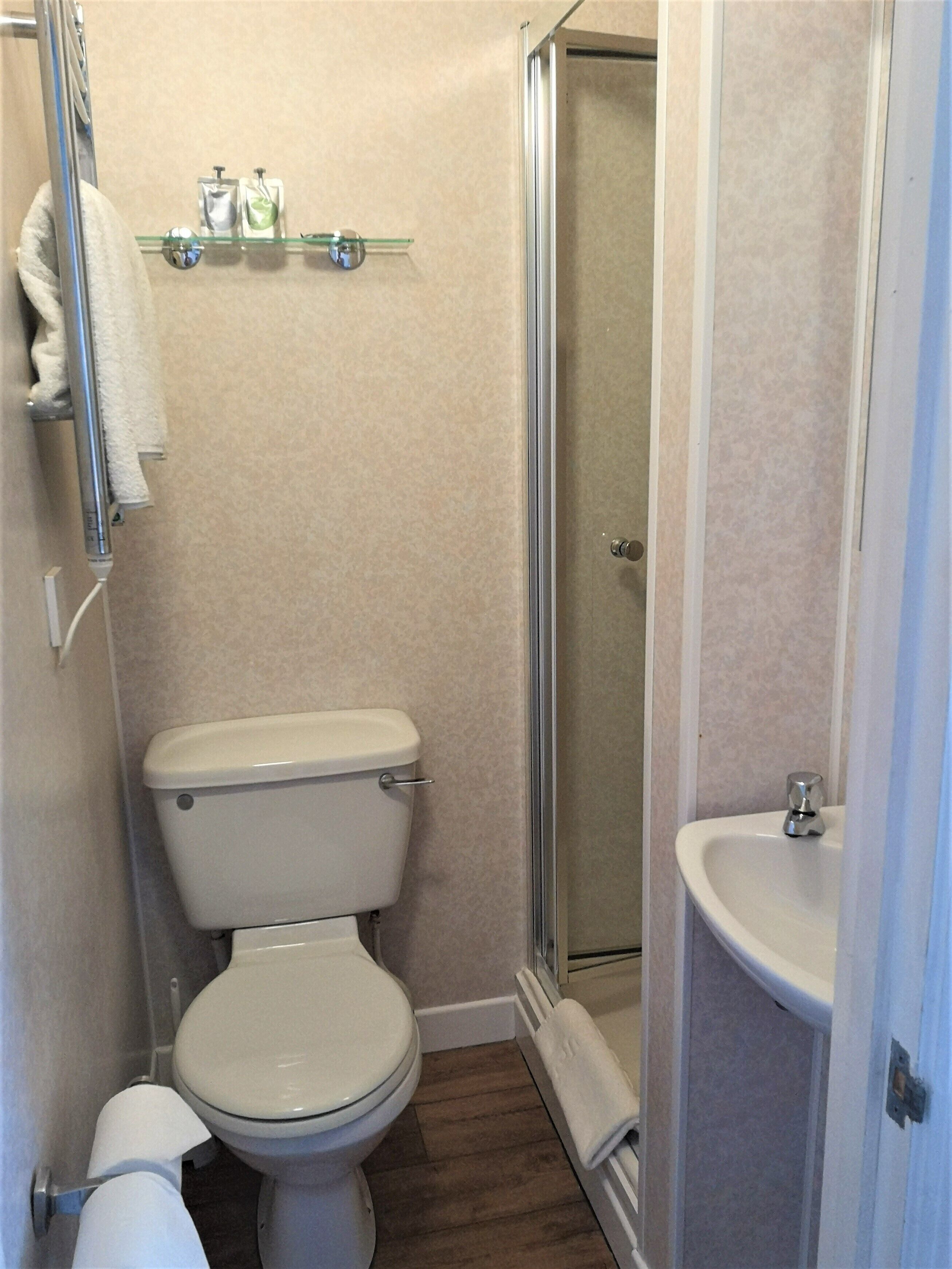 A compact bathroom with a toilet, a glass shower enclosure, and a sink.
