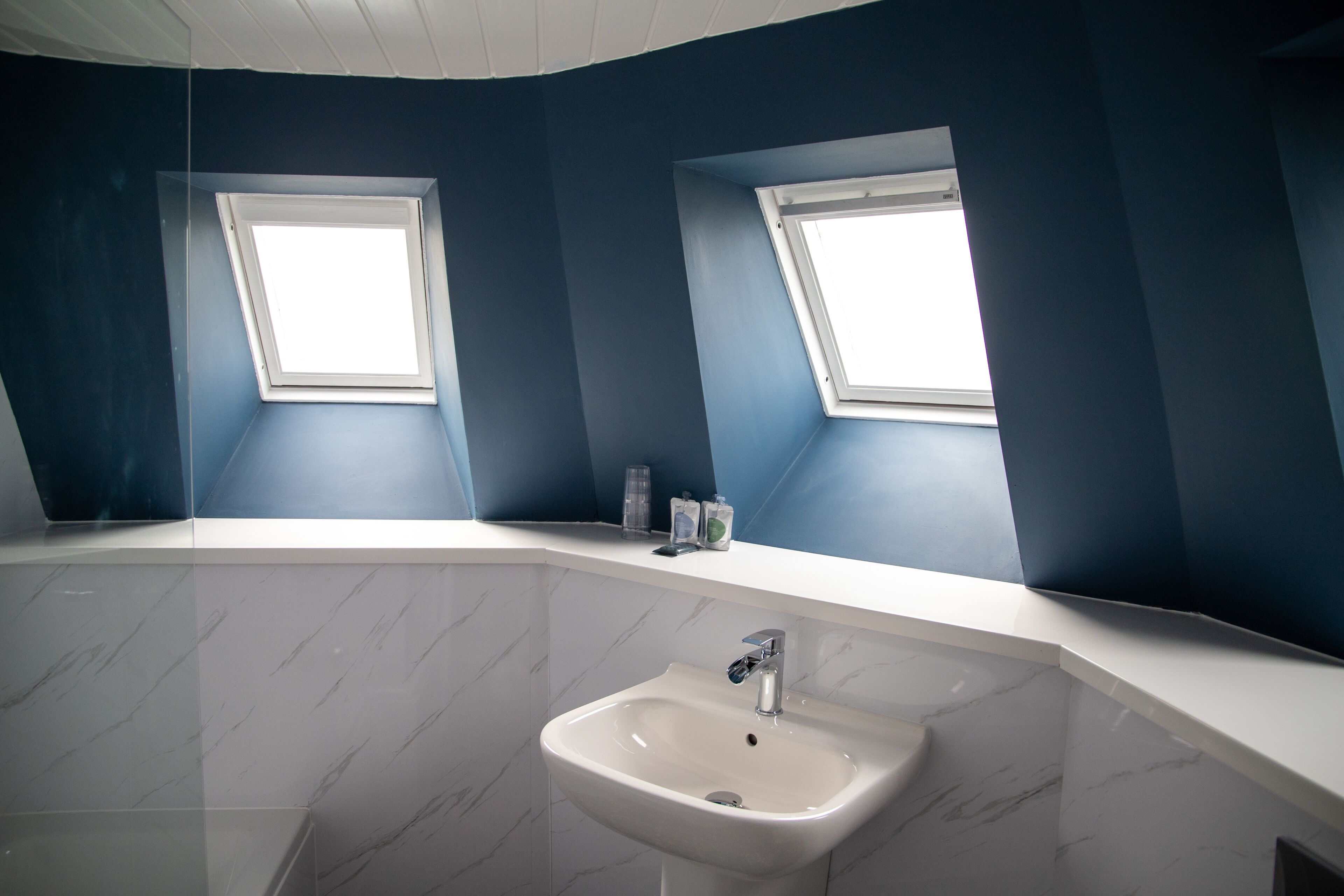 A bathroom with a white sink, two skylights, and a white vanity with a mirror.