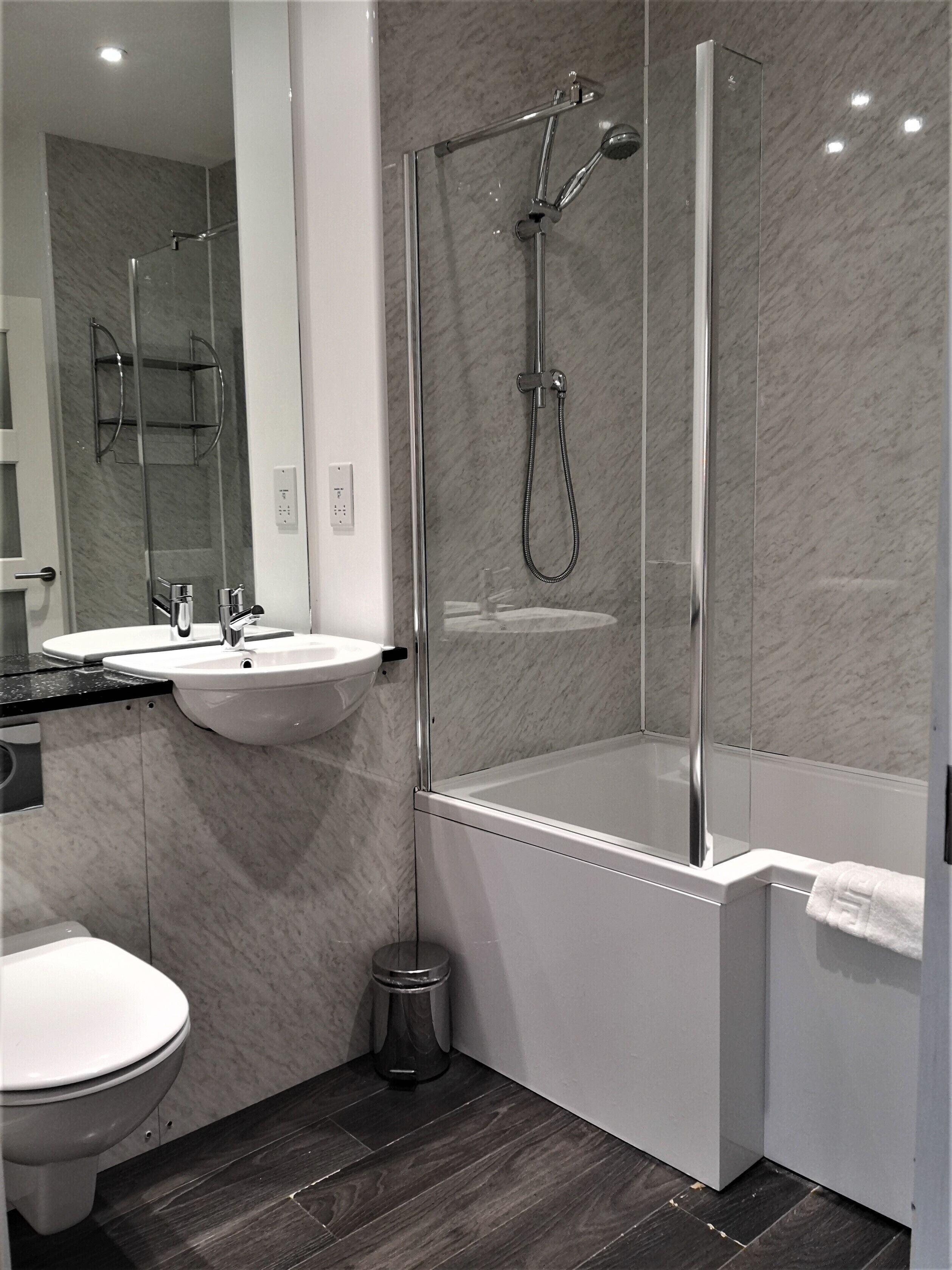 A modern bathroom with a glass-enclosed shower, a white sink, and a toilet.