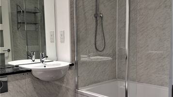 A modern bathroom with a glass-enclosed shower, a white sink, and a toilet.