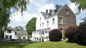 Un grand bâtiment en pierre, à l’extérieur blanc, doté de nombreuses fenêtres et d’un porche abrité.