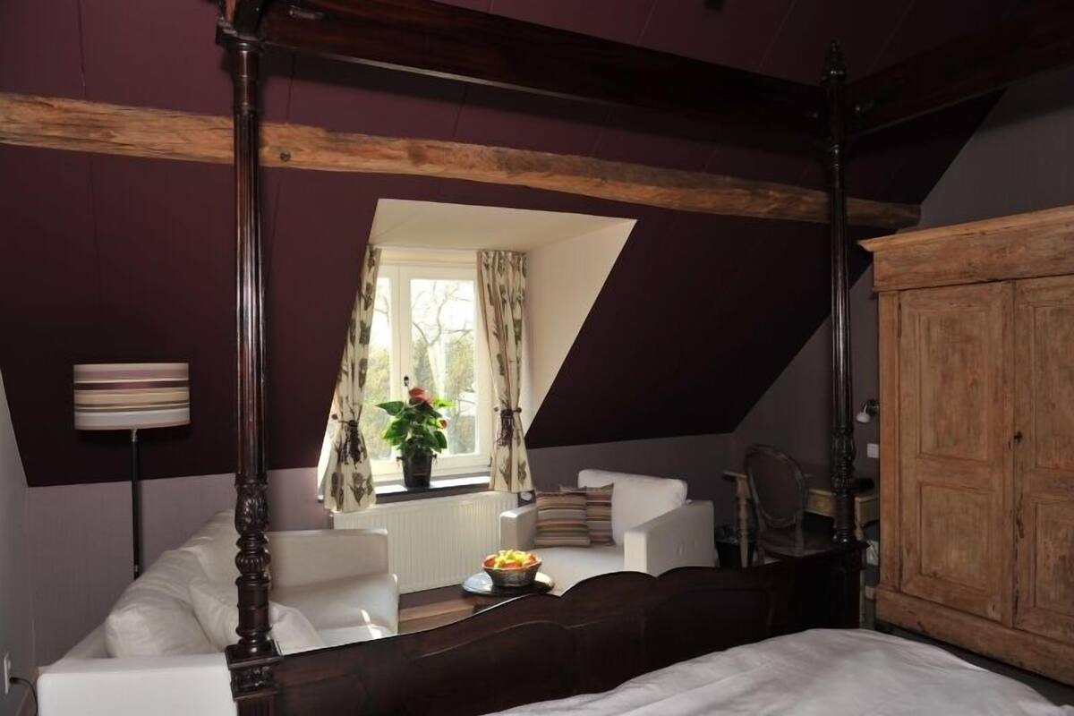 Une chambre à coucher avec un lit à baldaquin, une armoire en bois et une fenêtre avec des rideaux.