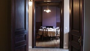 Un espace repas agrémenté d’un lustre, de portes en bois et d’un sol recouvert de moquette.