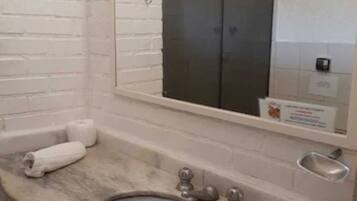 Une salle de bain avec un lavabo en marbre, un grand miroir et un porte-serviettes.