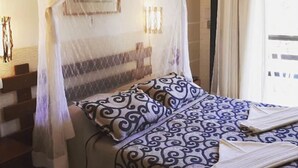 A bedroom with a bed, a nightstand, a window with curtains, and a wall-mounted lamp. - Hotel La Brise (Cabo Frio)