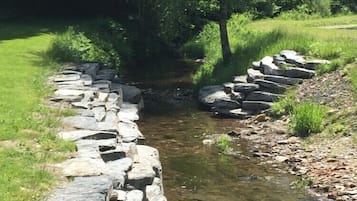 A natural stone bridge over a small stream in a lush green area.