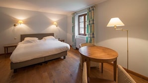 Une chambre d’hôtel avec un lit, une table en bois et deux lampes fixées au mur.