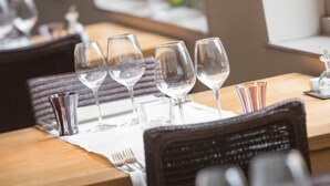 Un espace repas avec des tables mises pour le dîner, comprenant de la vaisselle en verre transparente et offrant une vue sur l’extérieur.