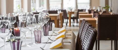 Un ambiente de restaurante con mesas dispuestas para comer, con vasos transparentes y velas.
