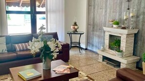 A living room with a fireplace, a sofa, a coffee table, and a chandelier. - Hotel Blumenhof (Blumenau)