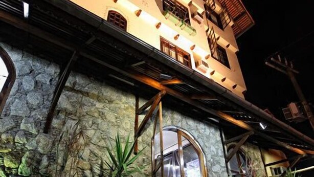 A multi-story building with a stone facade, a large arched entrance, and a staircase leading to the entrance. - Hotel Blumenhof (Blumenau)