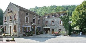 A stone building with multiple windows and a sign that reads "Hotel".