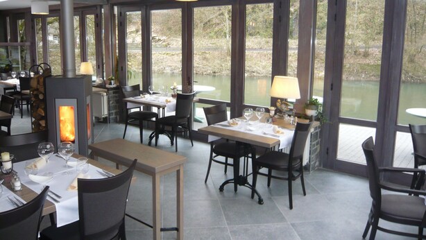 A restaurant with large windows, a fireplace, and a view of a lake. - Hotel a la Ferme (Ferrieres)