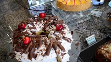 Una presentación de postres con un pastel cubierto de crema batida, virutas de chocolate y cerezas.