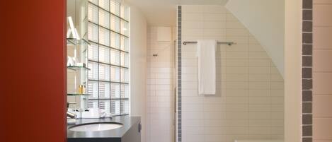 A modern bathroom with a glass shower enclosure, a white bathtub, and a vanity with a mirror.