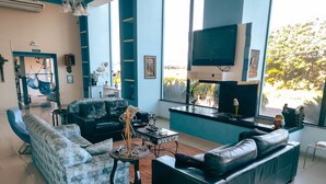A modern living room with a sofa, a coffee table, and a TV mounted on the wall. - Hotel Lago Azul (Bonito)