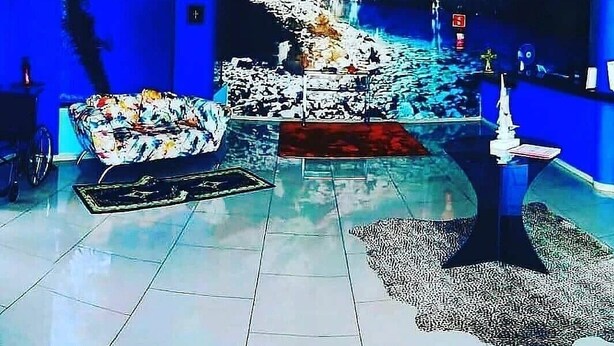 A modern living room with a blue wall, a sofa, a coffee table, and a decorative fountain. - Hotel Lago Azul (Bonito)