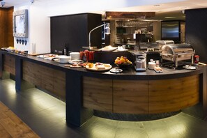 Un mostrador de buffet con diferentes alimentos, una estación de café y una parrilla.