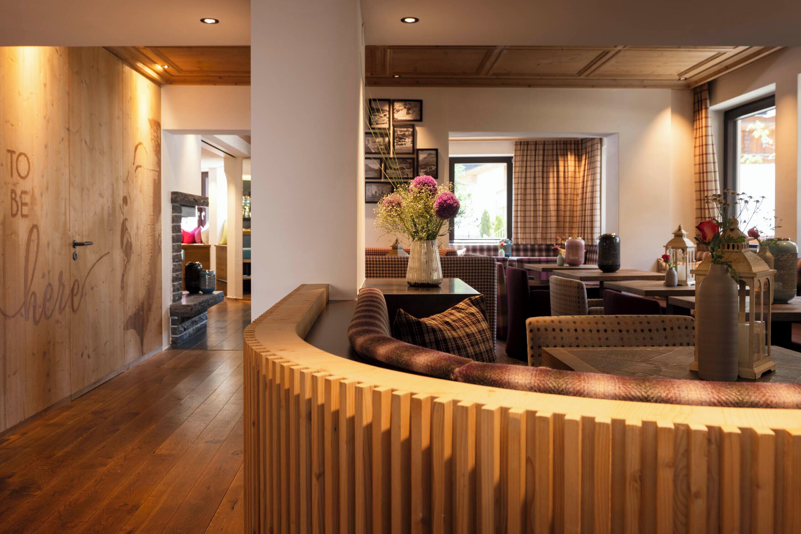 A modern living room with a wooden reception desk, a sofa, and a dining area with a table and chairs.