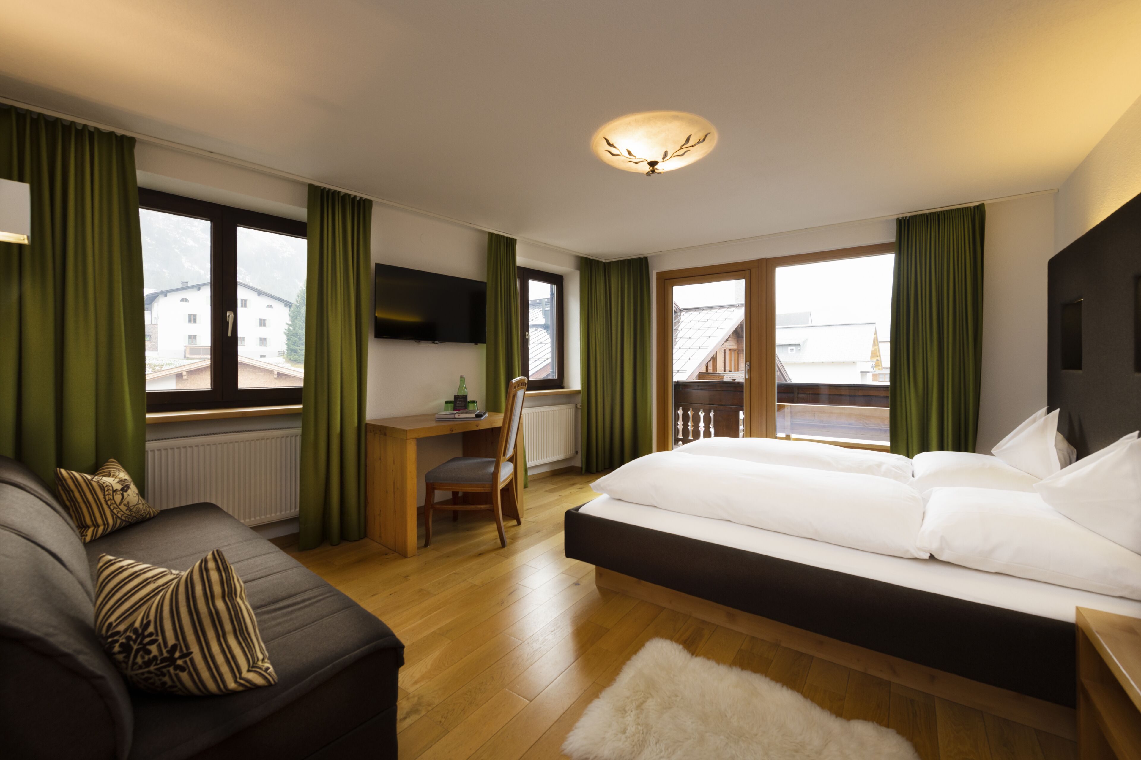 Una habitación de hotel moderna con una cama grande, un escritorio y un sofá.