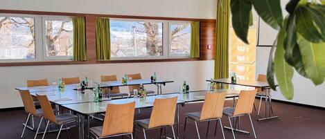 Una sala de conferencias con una larga mesa, sillas y ventanas con cortinas.