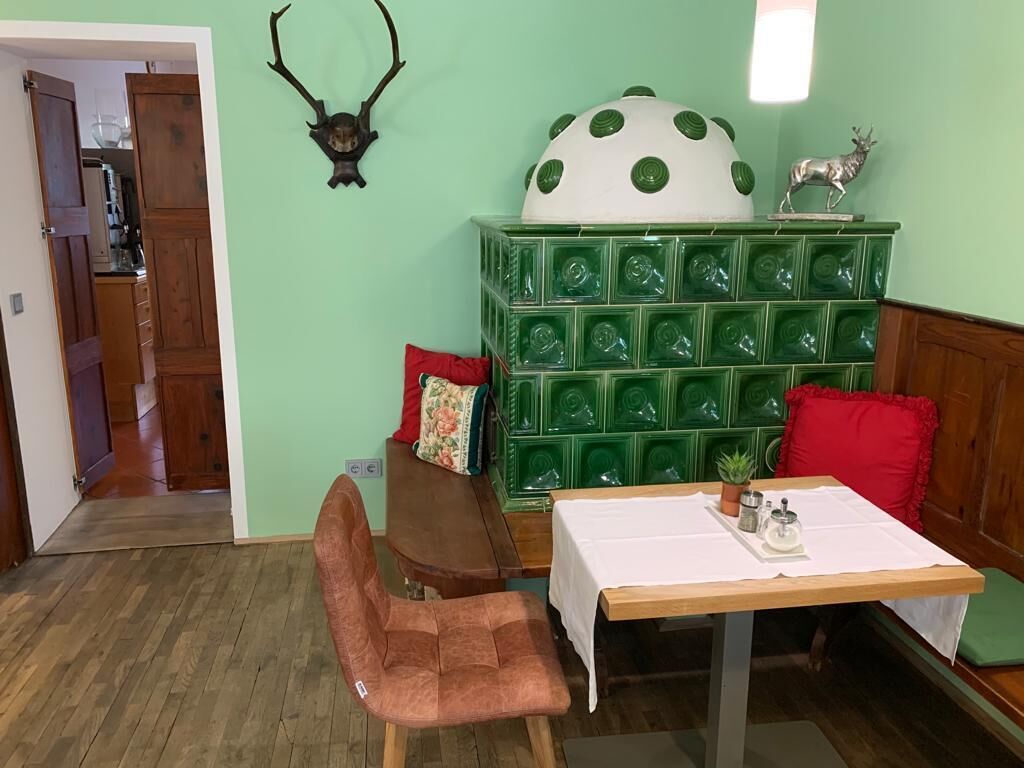 Uma área de refeições com mesa, cadeiras e um móvel de armazenamento verde com vários compartimentos.
