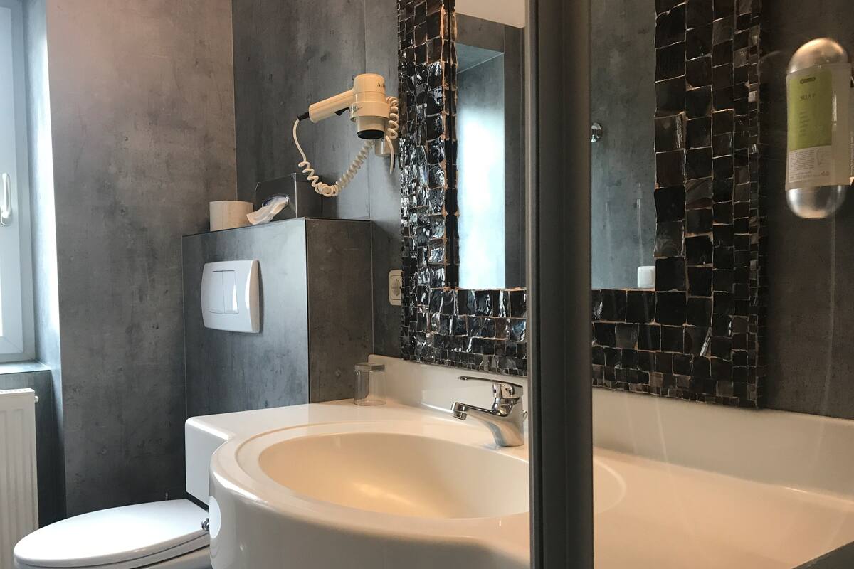 Ein Badezimmer mit einem weißen Waschbecken, einem Spiegel und einer Toilette.