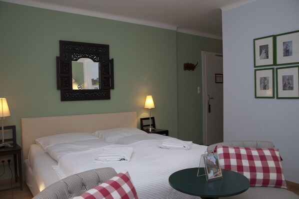 Una habitación de hotel con una cama, dos mesitas de noche, una mesa redonda y un espejo en la pared.